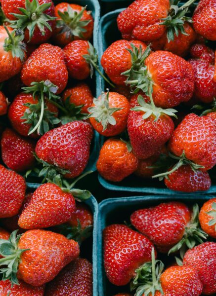 Fresh, ripe strawberries in green containers, showcasing their vibrant red color and green leaves, perfect for healthy snacking or dessert recipes.